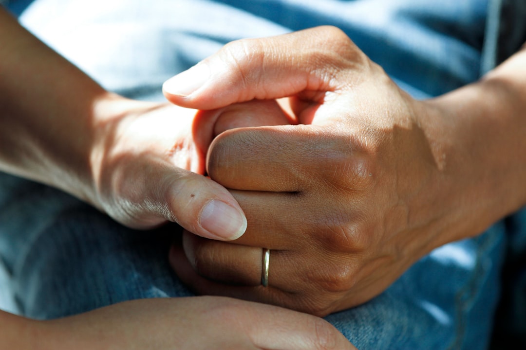 Close-up of two hands clasping together, suggesting support and care